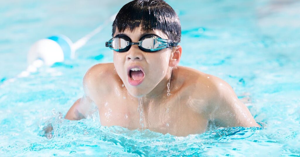 A young boy swimming with goggles in an indoor pool in Toronto, Canada.